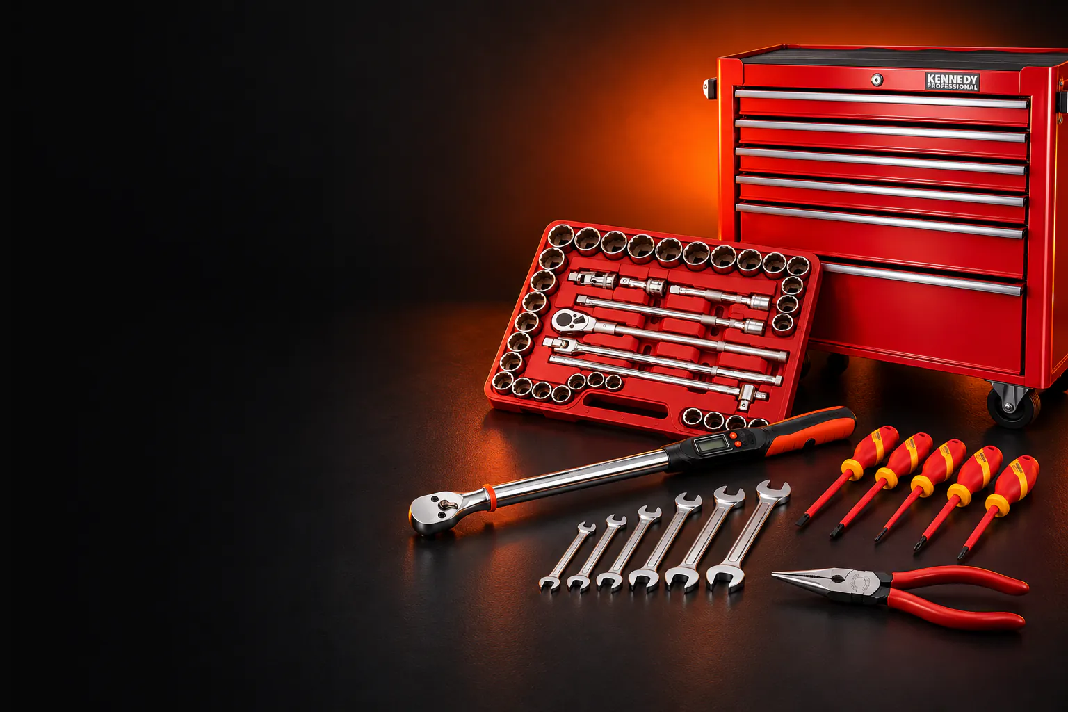 Kennedy tools from the Cromwell promotion: a red seven-drawer roller cabinet, a socket set in a red tray, a digital torque wrench, open-ended spanners, insulated screwdrivers and pliers on a black floor lit in orange